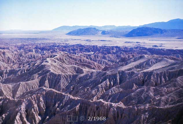 Color photo: Badlands in foreground w / hills in distance - Embedded text: 2/1968