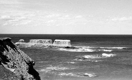 grayscale photograph: large rock fomations in water
