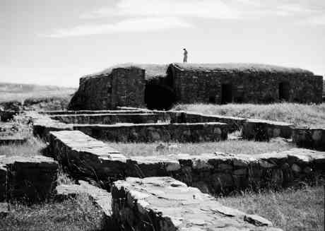 Masonry faced mound with ruins in foreground