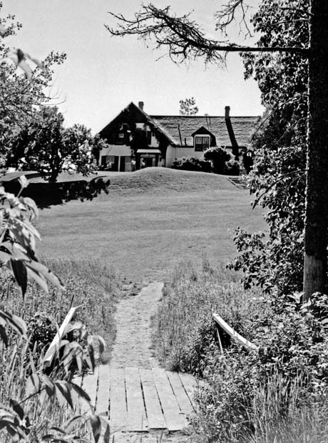 grayscale photograph: walkway bridge leading to house in distance