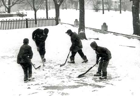 grayscale photograph: hockey players in the front yard