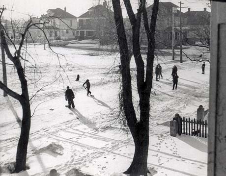 grayscale photograph: hockey palayers in the street