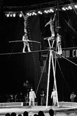 B/W photo: A performer atop head of tightrope walker
