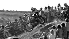 B/W photo: Midair motocross racer with spectators in foreground and background