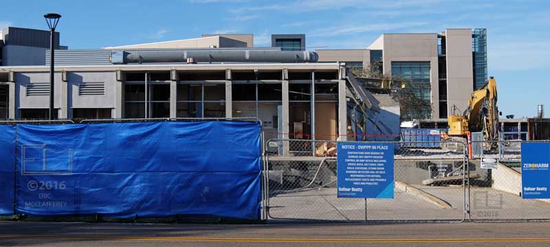 Partially blue curtained fence in front of loading dock area and not yet demolished portion of building