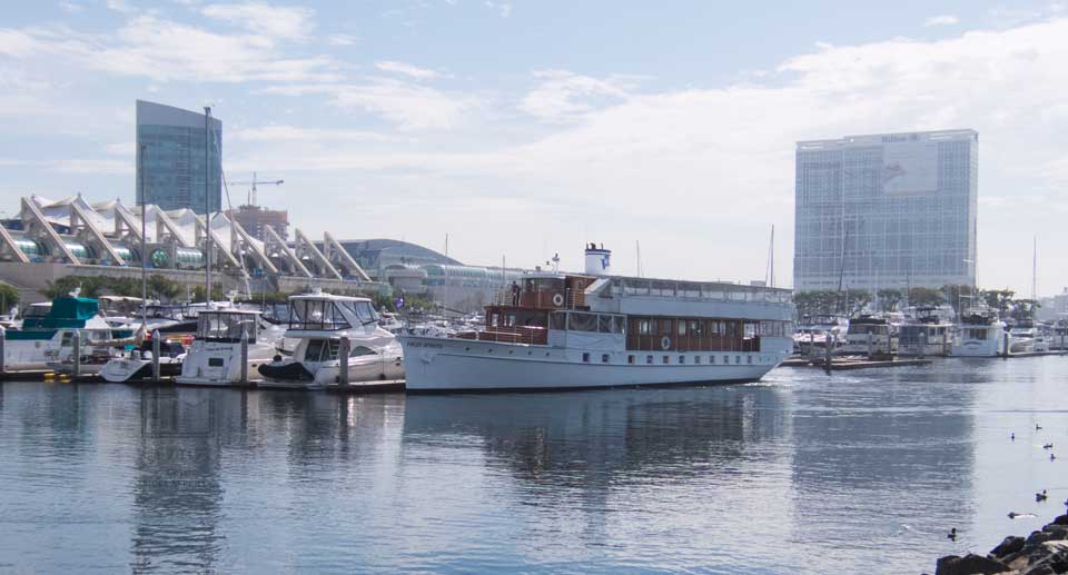 View accross water of yachts in marina with Convention Center and 2 high rise buildings in background