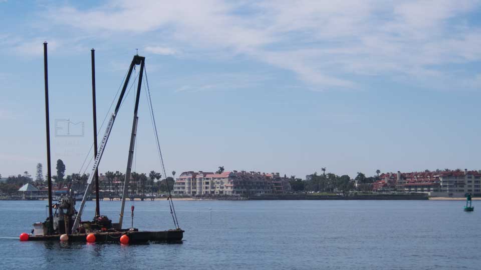 A small boat with a very large crane, Coronado apartment blocks in background