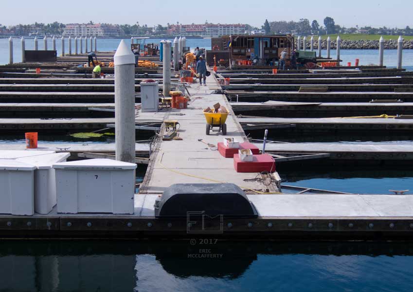 Empty section of moorings with tools and equipment laying about and workers in the distance