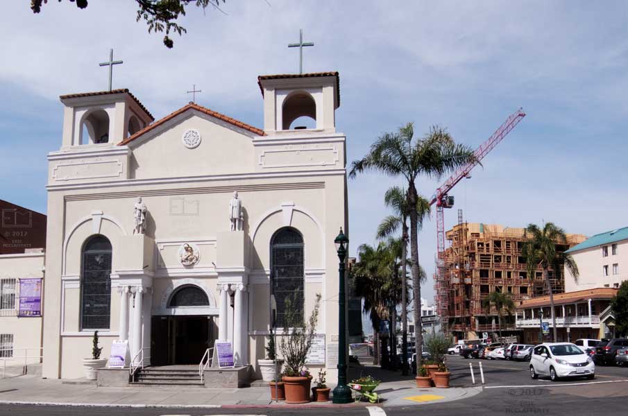 View of church in foreground with construction crane and uncompleted multi-story building in background