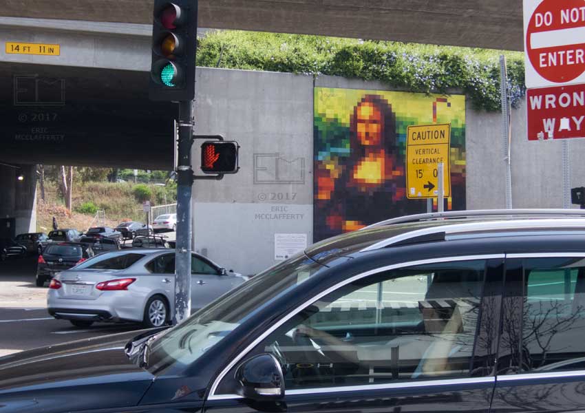 Busy view of multi-signed intersection with pixilated  street art, Mona Lisa, on freeway entrance