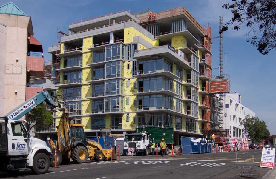 View of an under construction multi-storied building surrounded by construction equipment and supplies