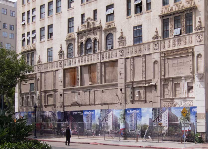 An abandoned, dilapidated multi-story building viewed from across street 