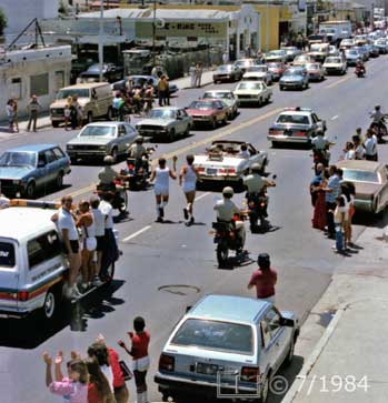 Color photo: Spectators view/applaud passing torch bearer and motercade  - Embedded text: 5/8/73