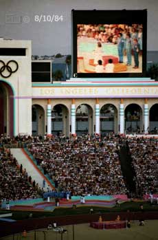 Color photo: Presentation being made and displayed on large screen monitor  - Embedded text: 8/10/84