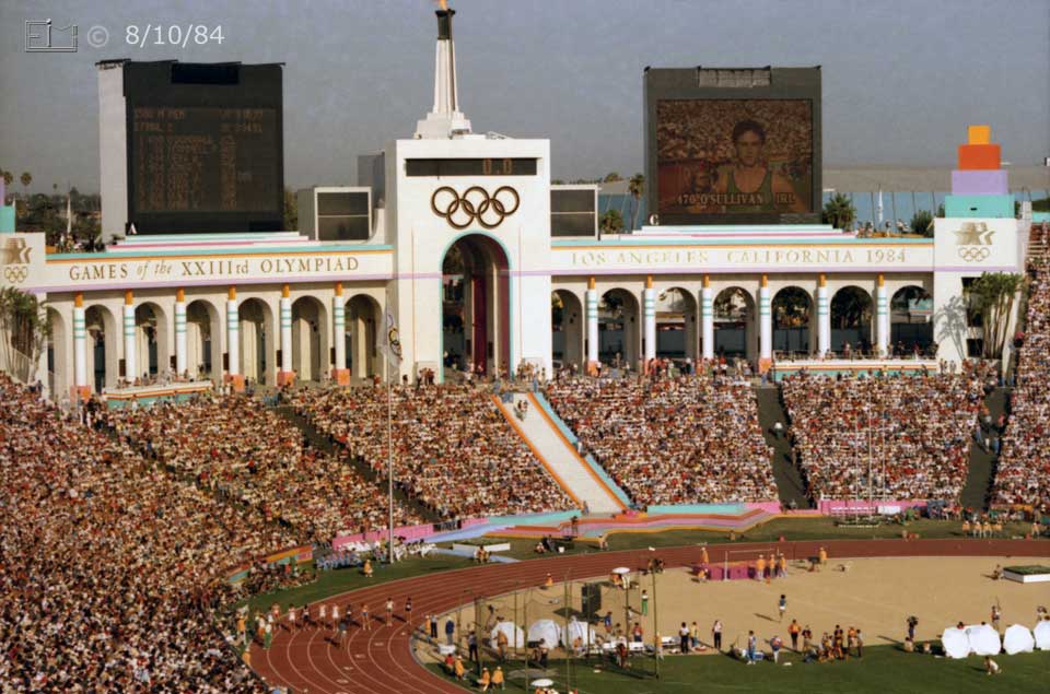 Color photo: Men prepare to start 1500 meter race with Coliseum's colonnade/arcade as backdrop - Embedded text: 8/10/84