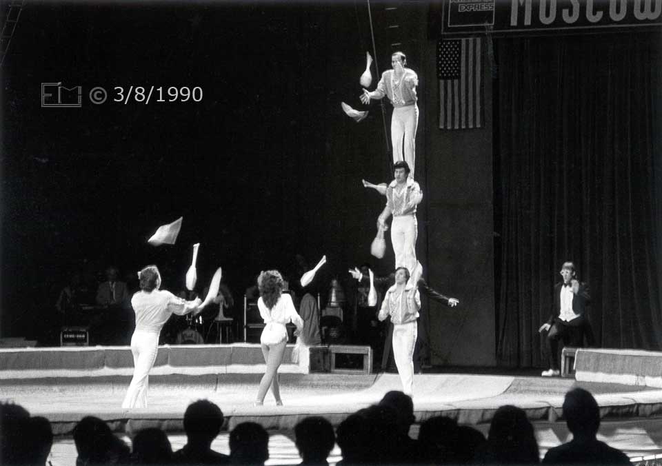 B/W photo: Column of 3 jugglers, astride each other, exchanging pins with 2 other jugglers - Embedded text: 3/8/1990