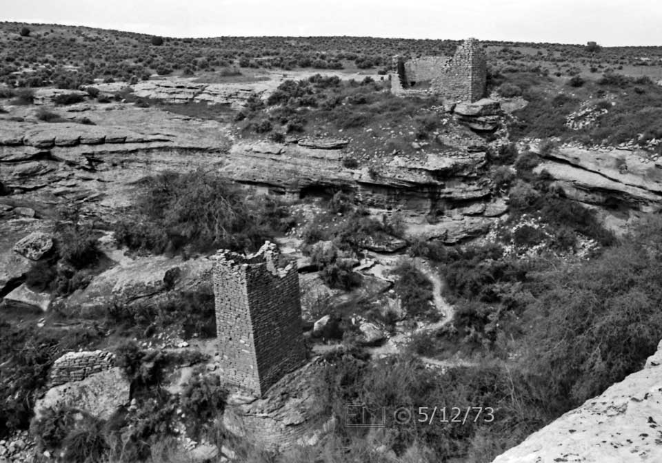 B/W photo: Square tower ruin in canyon and  ruin on masa beyond - Embedded text: 5/12/73