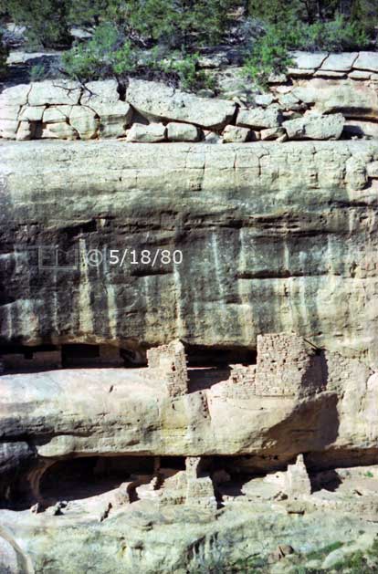 Color photo: Front portrait view of cliff dwelling ruins from across canyon - Embedded text: 5/18/80