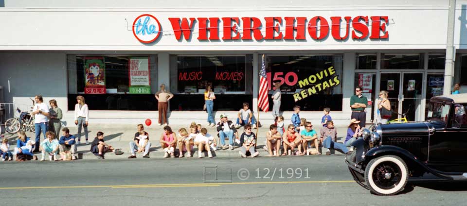 Color photo: Antique car passes by curbside seated spectators - Embedded text: 12/1991