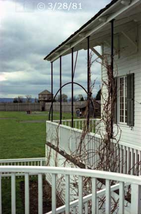 Color photo: View from atop dual staircase of veranda and distant watch tower and palisades - Embedded text: 3/28/81