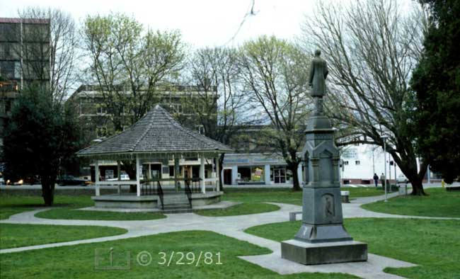 Color photo: Landscape view of park with statue facing small bandstand - Embedded text: 3/29/81