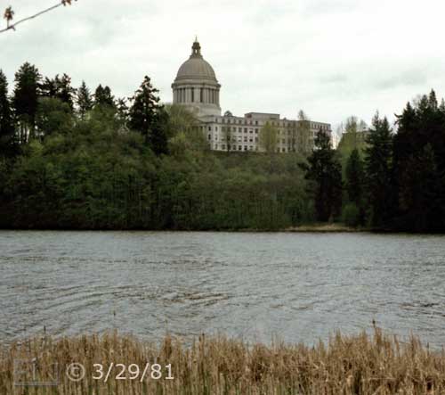Color photo: View accross water of tree lined shore and back of State Capital building - Embedded text: 3/29/81