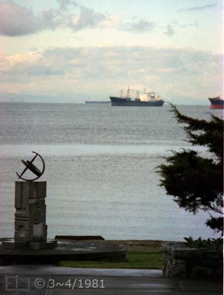 Color photo: Portrait view of small monument on shore and freighters in distance - Embedded text: 3~4/1981