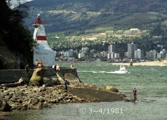 Color photo: Low tide view of lighthouse, man fishing and apartment blocks on far shore - Embedded text: 3~4/1981