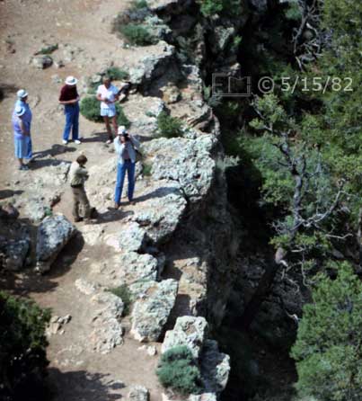 Color photo: Spectators atop cliff taking pictures - Embedded text: 5/15/82