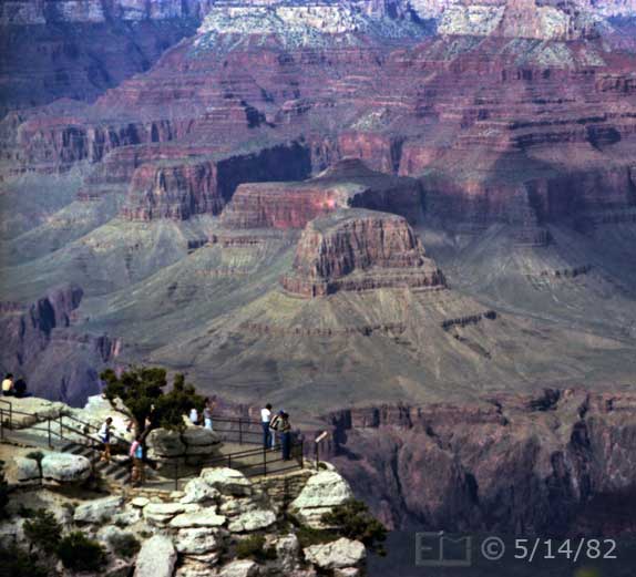 Color photo: Downward looking view of spectators on overlook with Sumner Butte and other rock formations on far side of canyon as backdrop - Embedded text: 5/14/82
