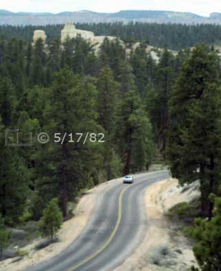 Color photo: Elevated view of highway through forest with large rock formation in distance - Embedded text: 5/17/82