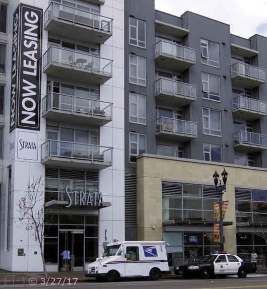 Color photo: A new apartment building with a large 'Now Leasing' sign - Embedded text: 3/27/17