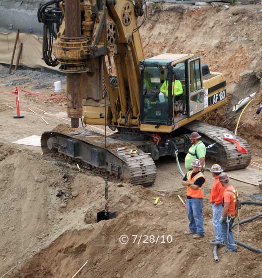 Color photo: I-beam pier, of future retaining wall, implanted in posthole - Embedded text: 7/28/10