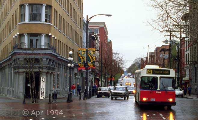 Color photo: Bus and street traffic along side of 'Flatiron' style building - Image taken: 4/7~12/1994