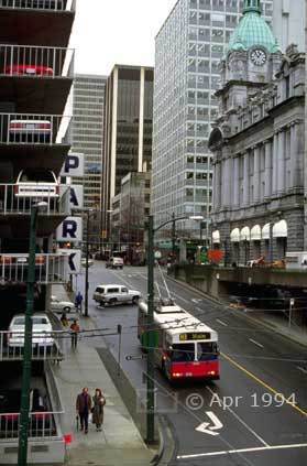 Color photo: Street scene with multi-story parking structure on left and building with copper domed clock tower across street - Image taken: 4/7~12/1994