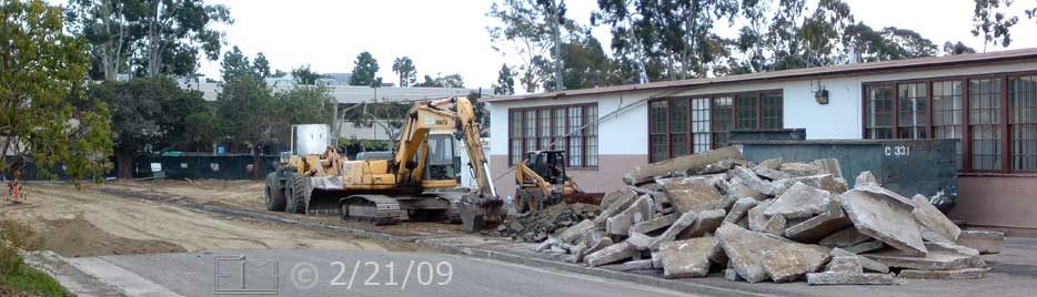 Color photo: Machinery, piled rubble, dumpster in front of east side of old building - Embedded text: 2/21/09