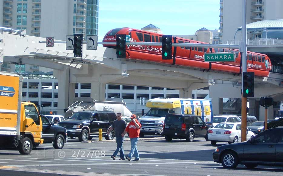 DSC color photo: Pedestrians crossing Sahara Ave with elevated tram/tramway above in background - Embedded text: 2/27/08