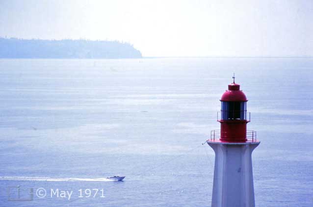 Color photo: Landscape view of speedboat with upper portion of light-house in foreground - Lighthouse Park? North Vancouver - Embedded text: May 1971