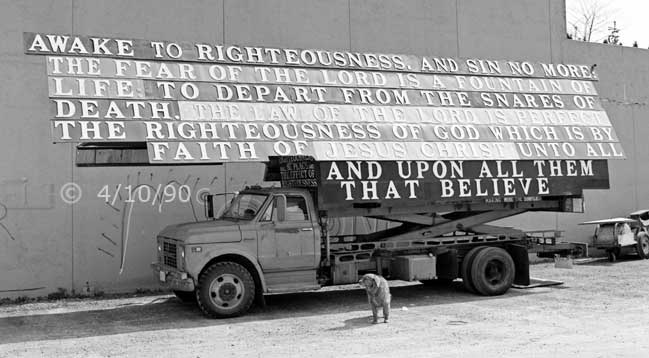 B/W photo: Large religious sign mounted on a heavy truck - Embedded text: 4/10/90