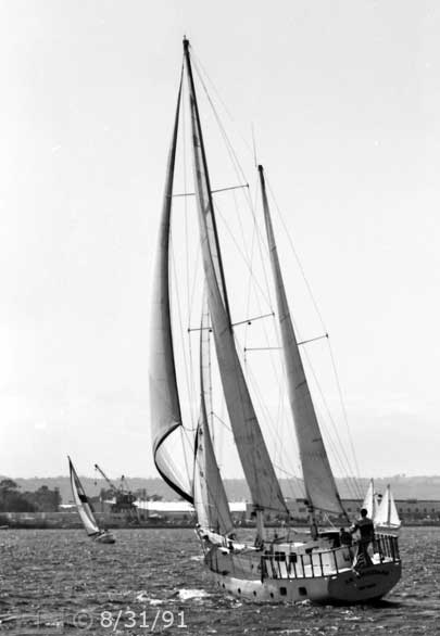 B/W photo: Port-stern view of boat under sail with Coronado in background - Embedded text: 8/31/91