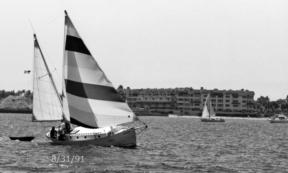 B/W photo: A boat under sail with apartments on the Coronado shore in background - Embedded text: 8/31/91