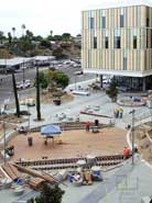 Color photo: Workers building a wooden platform with Student Services building in background