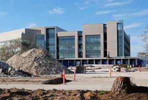 Color photo:  View from Mesa College Circle of tree stump and rubble piles in front of the Math/Science building